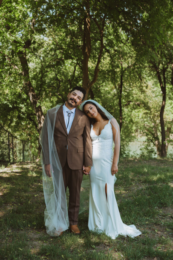 Bride and groom leaning against each other in the woods of The Texas Hill Country