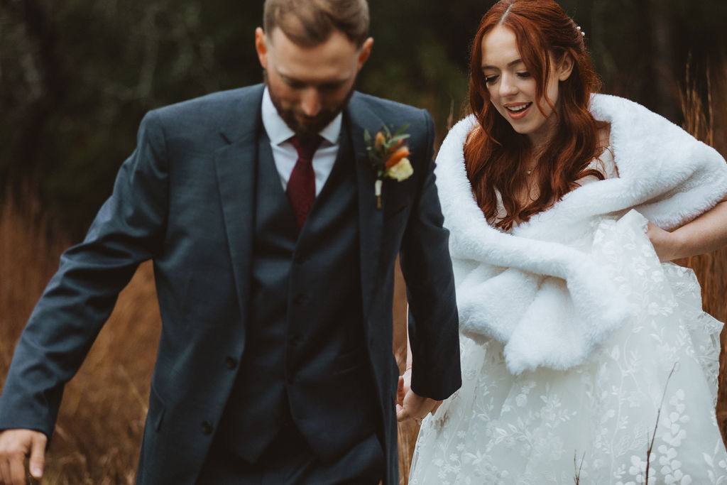 Bride and groom walk through field with fall colors