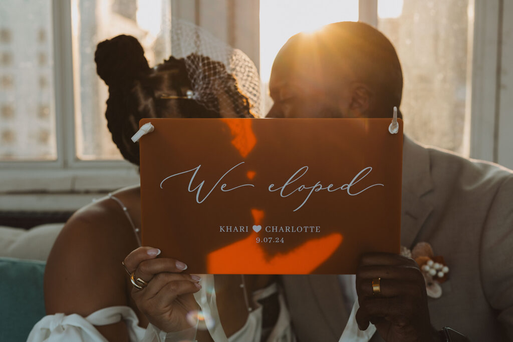 couple kissing behind an elopement sign