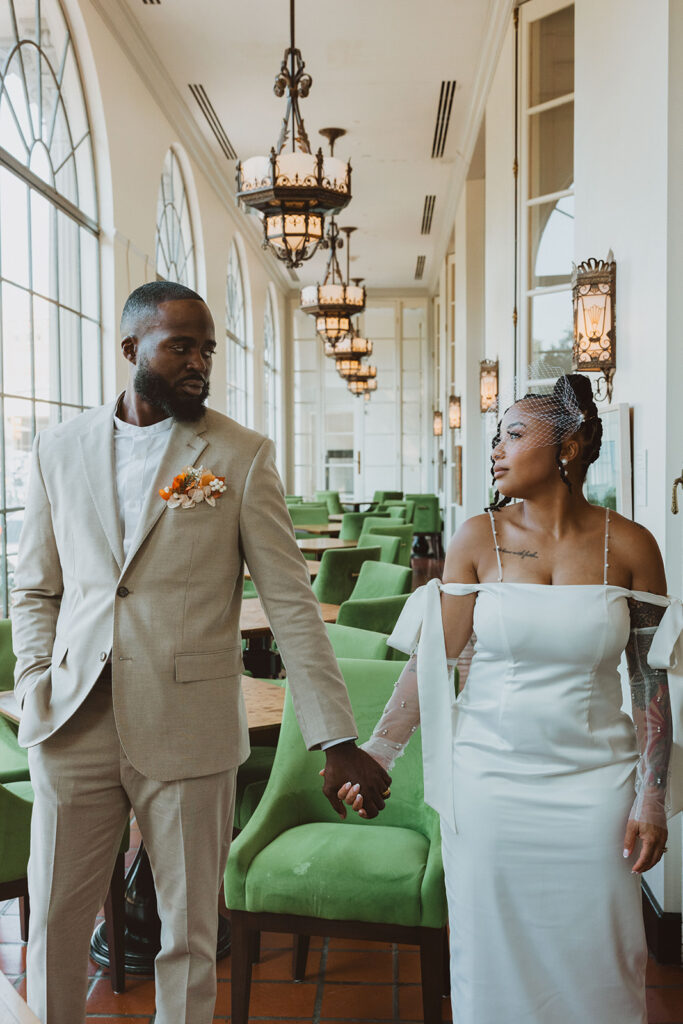Bride and groom hold hands in a breezeway in The Saint Anthony Hotel