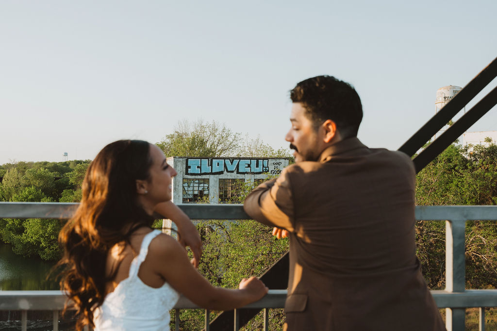 Bride and Groom stand out of focus with an I love you sign in focus begind them