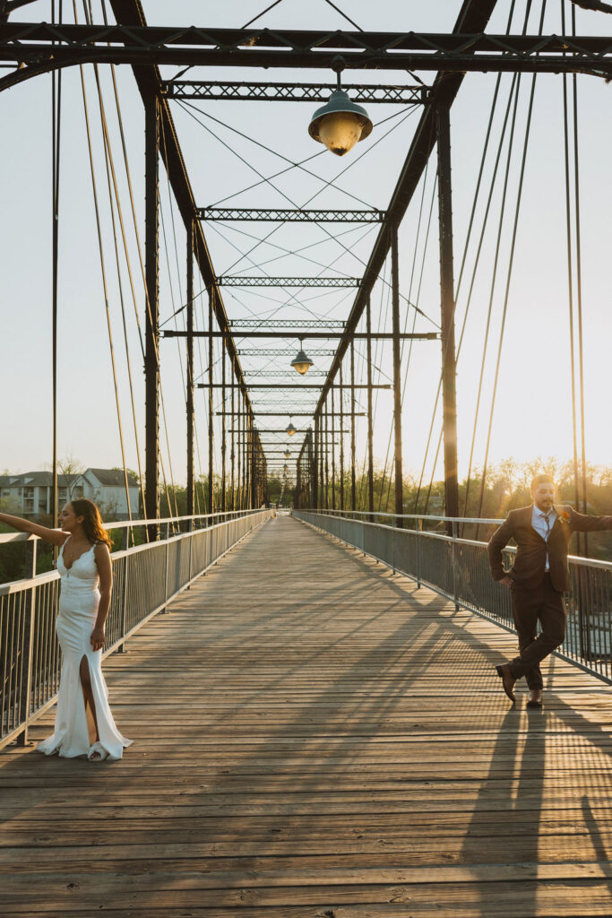 Bride and Groom stand on separate sides of a bridge during sunset