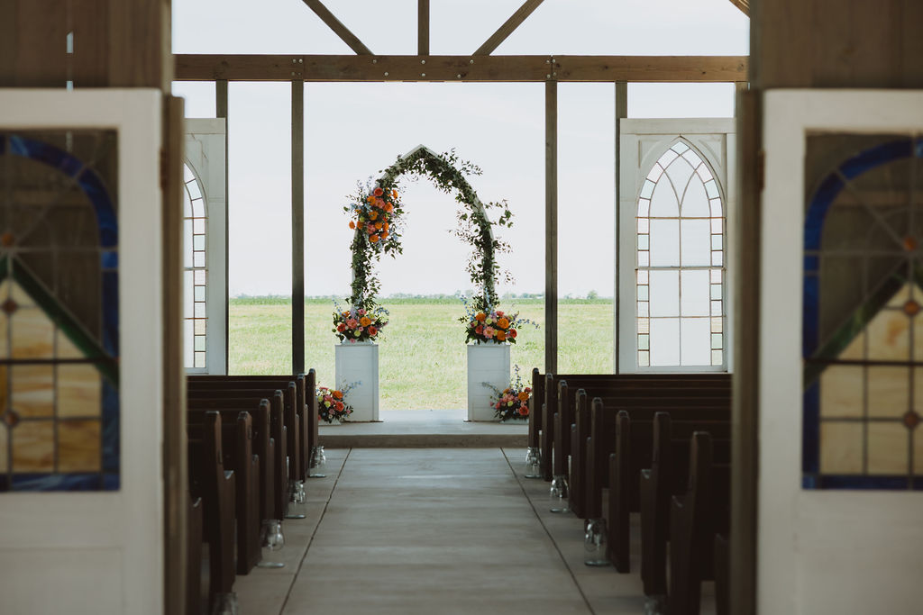 An alter pictured with a floral arch inside of an outdoor chapel