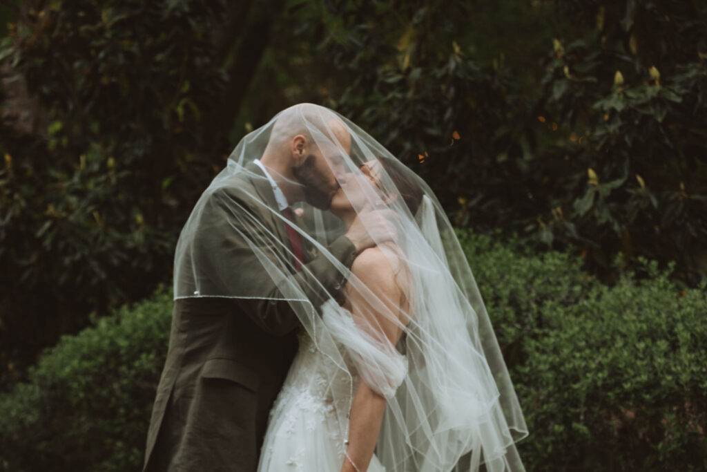 A bride and groom share a kiss underneath the bride's veil
