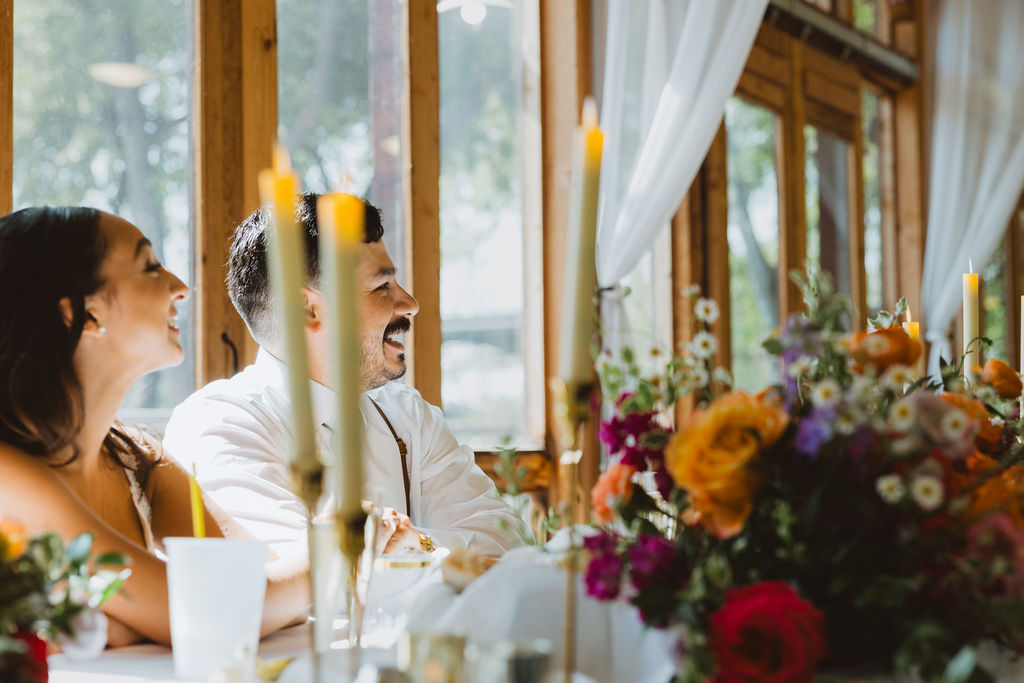 A shot of a bride and groom reacting joyously through flowers and candles