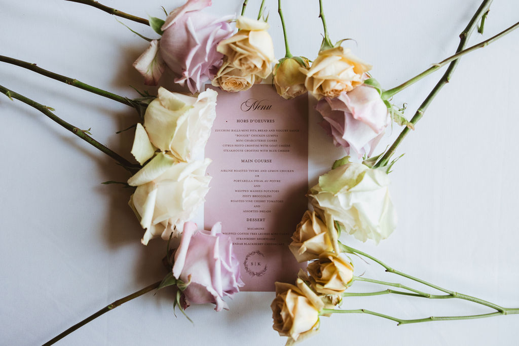 A food menu surrounded by pastel colored roses