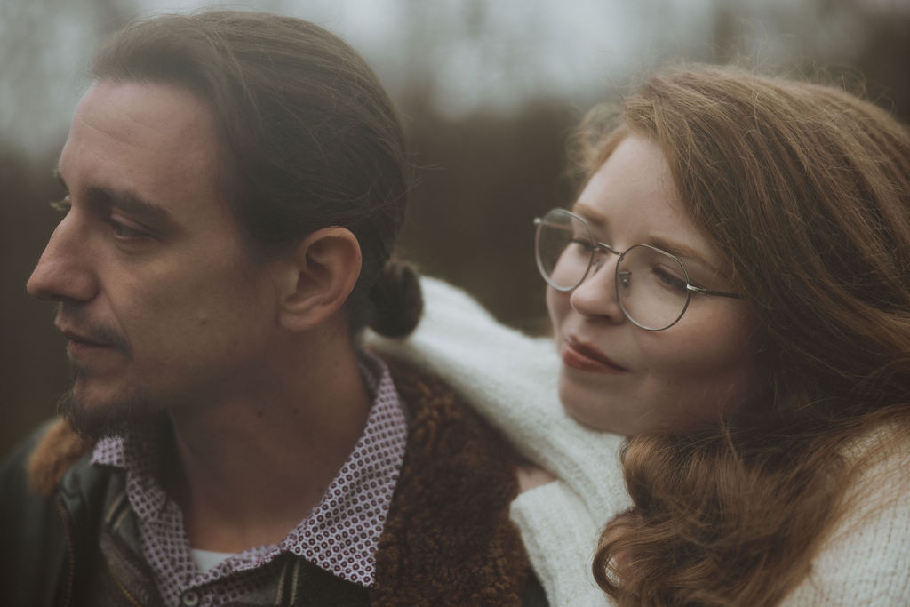 A couple sits close together looking off at something together